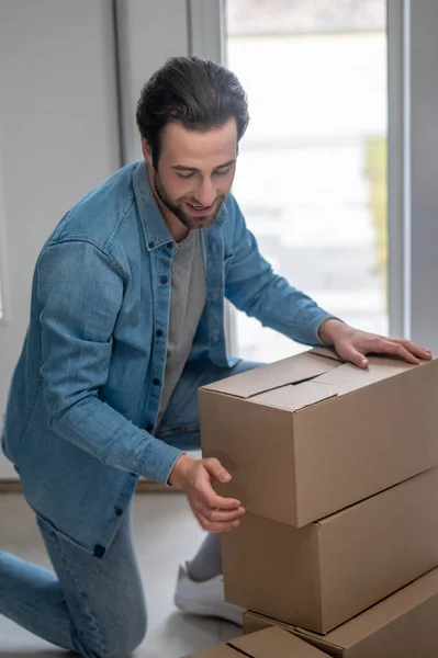 Accuracy Smiling Young Adult Man Kneeling Stacking Boxes Hallway New — Stock Photo, Image