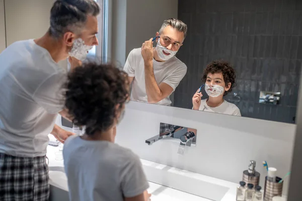 シェービングの芸術 パパは息子に剃り方を教える — ストック写真