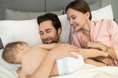 Mutlu bir an. Mutlu genç sakallı adam sevgiyle sarılıyor yalancı küçük çocuk ve kadın evde yatarken izliyor.