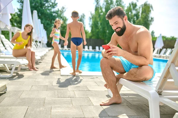 Joyful Male Vacationer Sitting Sunlounger Reading Text Message His Smartphone — Stock Photo, Image