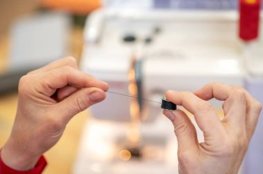 İplik kalınlığı. Ellerinde dikiş makarası var. Kapalı alanda kameraya gösteriliyor. Yüzü yok.