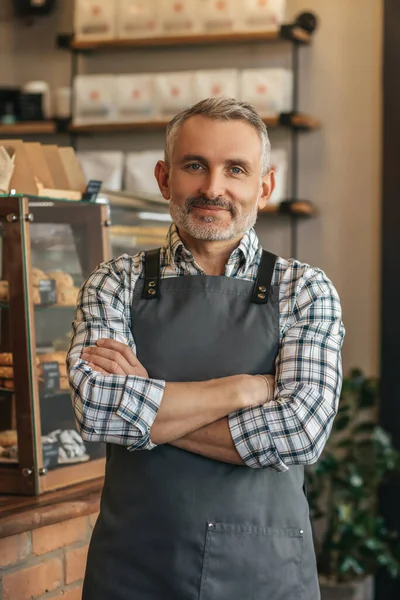 专业的 头戴围裙 自信的中年男子双手交叉放在胸前 看着站在咖啡店里的相机 — 图库照片