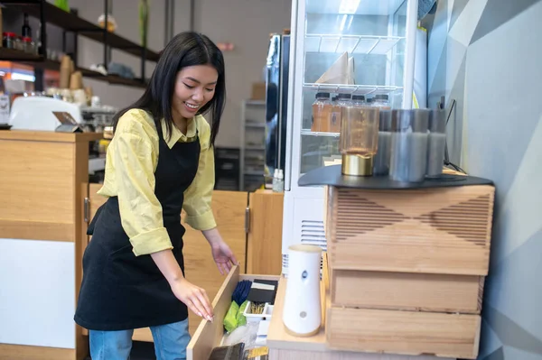 Suche Zufriedene Junge Asiatin Schürze Öffnet Schublade Schrank Arbeitsplatz Café — Stockfoto