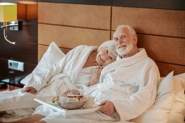 Good time. Senior couple spending weekend in a hotel and looking contented