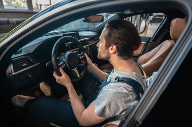 Araba teftişi. Araba denetimi için araba tamirhanesinde oturan genç bir tamirci.