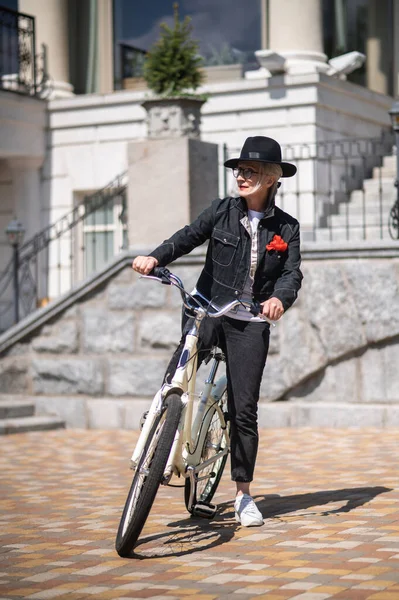 Happy ride. A woman in black with a bike in the city