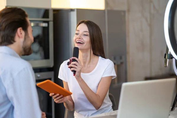 Interview. Pretty young journalist interviewing a famous person in a studio