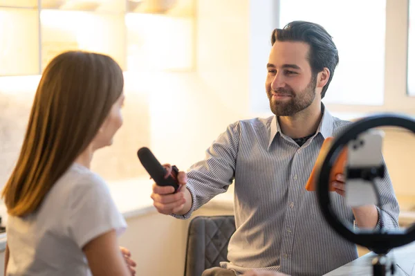 Interview in a studio. Young bearded journalist interviewing a long-haired woman