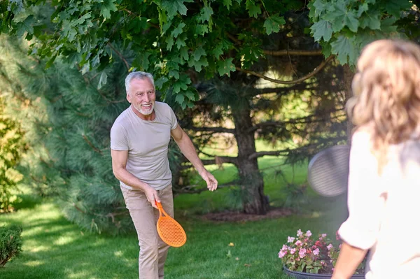 Oynuyorum. Parkta tenis oynarken eğlenen olgun bir çift.