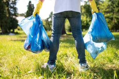 Garbage gathering. Close up of a person with bags with garbage in hands