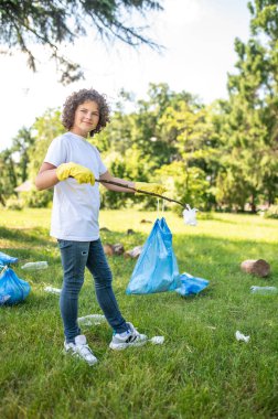 Volunteer. Cute young volunteer cleaning the park from plastic garbage