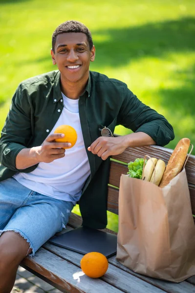 Vitamins Dark Skinned Guy Smiling Camera Holding Orange Sitting Bench — Foto de Stock