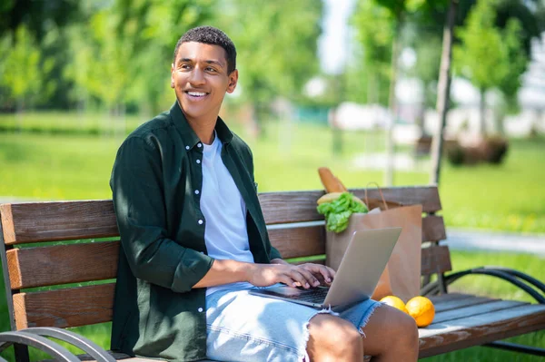 Pensamientos Hombre Joven Piel Oscura Trabajando Ordenador Portátil Sonriendo Pensativamente — Foto de Stock