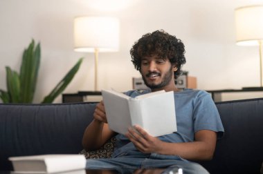 Kitap okuyordum. Kıvırcık saçlı Hintli adam kitap okuyor ve ilgili görünüyor.
