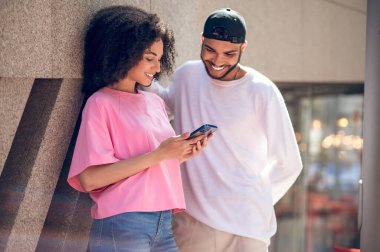 Sevimli bir çift. Siyah şapkalı genç adam ve sokakta pembe tişörtlü bir kadın.