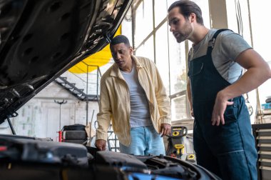 Araba servisi. Araba servisindeki teknisyen müşteriyle konuşuyor.