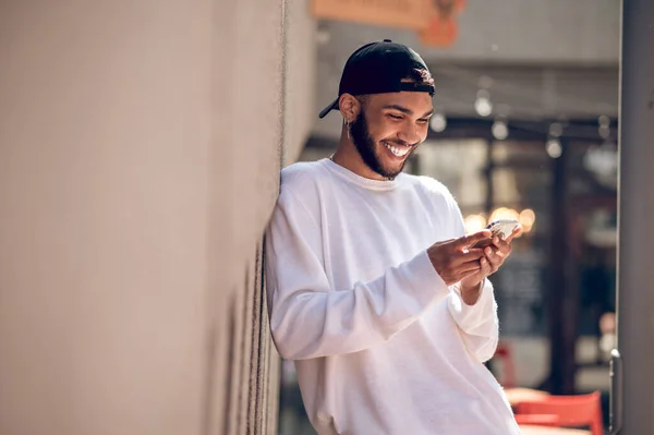 Man with a phone. Handsome man in a black cap with a smartphone in the street