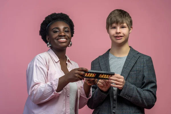 Inclusive education. African american woman and caucasian disabled guy holding abacus smiling at camera standing against light background