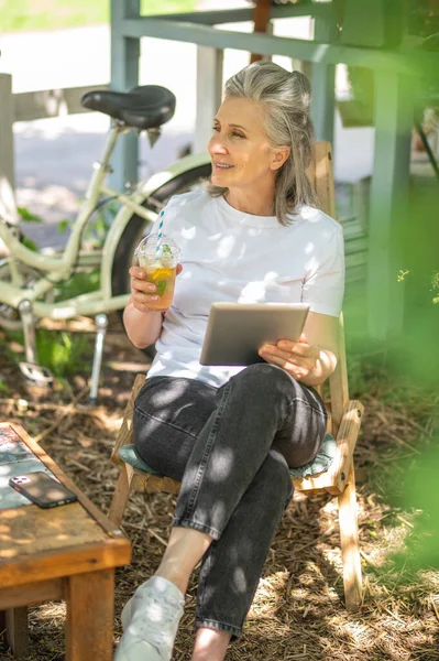 Surfing internet. A woman sitting outside with a talet and watching something online