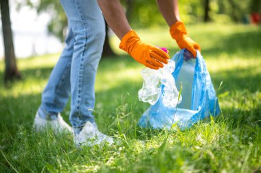 Ekoloji koruması. Sunny Park 'taki çimlerden plastik enkaz toplayan adamın elleri.