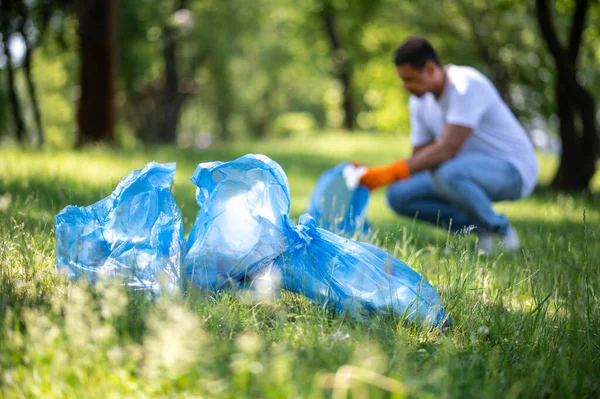 Environmental Pollution Garbage Bags Grass Man Crouched Collecting Garbage Green — Foto de Stock