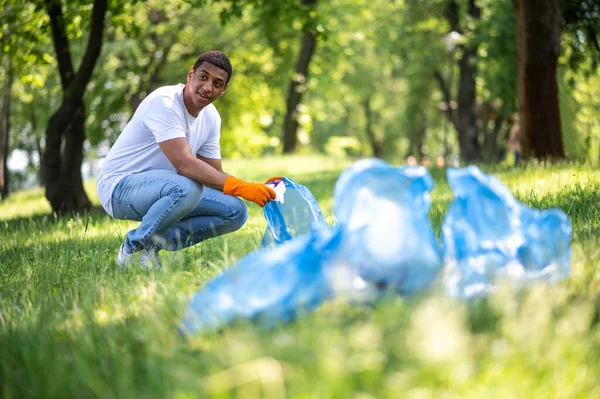 Ochrona Środowiska Naturalnego Młody Ciemnoskóry Mężczyzna Rękawiczkach Pakujący Śmieci Trawy — Zdjęcie stockowe