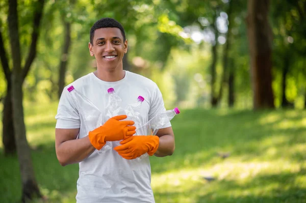 Optimism Dark Skinned Man Gloves Smiling Camera Standing Plastic Bottles — Foto Stock