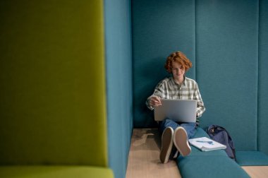 İnternette. Kızıl çocuk elinde dizüstü bilgisayarla oturmuş internetten bir şeyler izliyor.