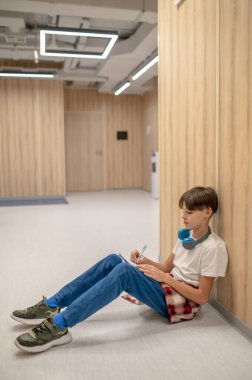 Homework. A boy sitting on the floor and doing his homework