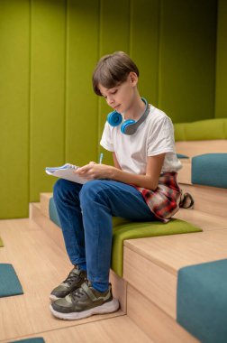 Okulda. Bir okul çocuğu bir şeyler yazıyor ve ilgili görünüyor.