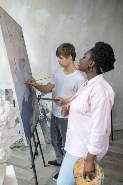 Inspiration. A boy standing near the easel and drawing with great involvement