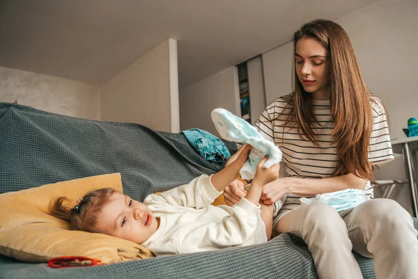 Caring Beautiful Young Woman Seated Sofa Changing Diaper Her Cute — стоковое фото