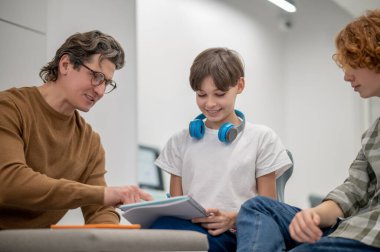 Okulda. Gözlüklü öğretmen öğrencilerine bir şey anlatıyor.