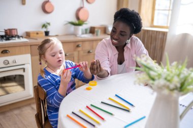 Home schooling. African american woman and a girl learning colors and drawing