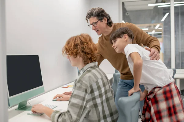 Lesson at school. Schoolboys and their teacher at the computers in a classroom