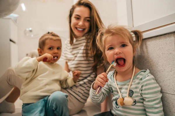 Cute Little Girls Sitting Bathroom Floor Brushing Teeth Supervised Mother — Foto de Stock
