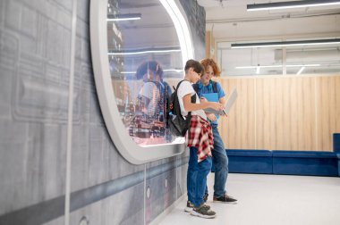 Modern okul. Modern bir okulun penceresinin yanında duran iki arkadaş.