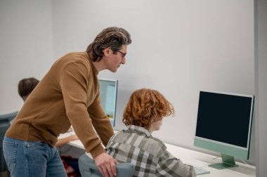 Okuldan bir ders. Okullu çocuklar ve öğretmenleri sınıftaki bilgisayarların başında.