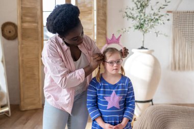 Little princess. African american woman putting a crown on head of a girl in blue dress