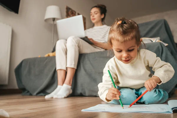 Young Woman Typing Laptop While Her Daughter Sketching Pencils Sketchbook — Stockfoto