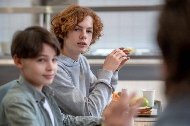 Talk at lunch. Teens and their teacher in a chool canteen