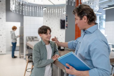 Talk with teacher. Teacher talking to a school boy in a school canteen