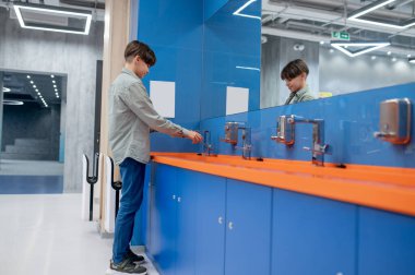 Washing hands. A boy washing hands in a school toilet