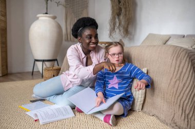 Studying. A girl with down syndrome reading something with her teacher