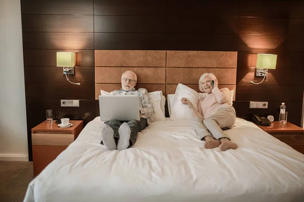 Online Senior Couple Lying Bed Gadgets Hands —  Fotos de Stock