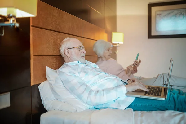 Online Senior Couple Lying Bed Watching Something Online — Stock Fotó