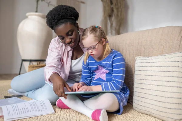 Studying. A girl with down syndrome reading something with her teacher