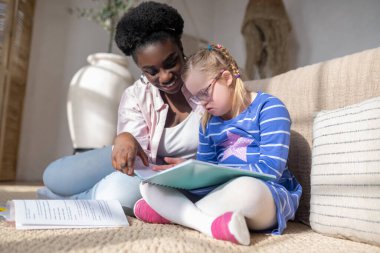 Studying. A girl with down syndrome reading something with her teacher