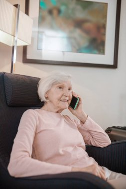 Modern technologies. Elderly lady in beige blouse with a smartphone in hand