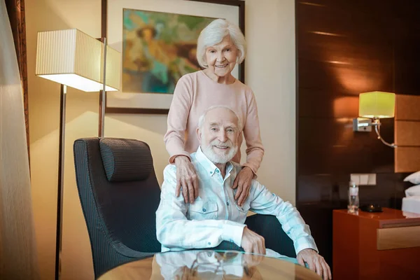 Life partners. Elderly couple in a nice room looking happy and peaceful